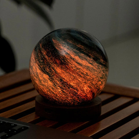 Glass sphere with fiery orange and black interior on a wooden surface