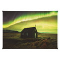 A rectangular fridge magnet showing a small dark church in a flat landscape under a dramatic green and yellow aurora sky