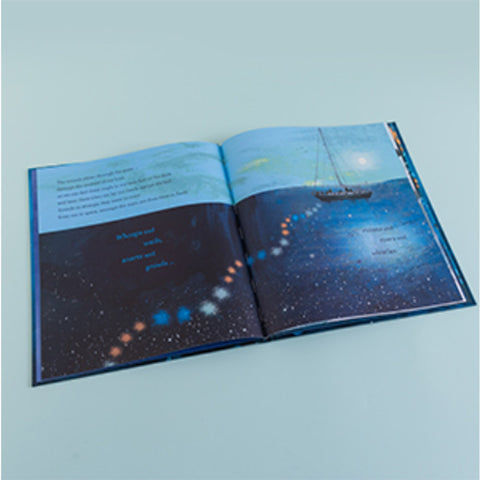 Open book with a starry night design and a boat on the sea on a light blue background
