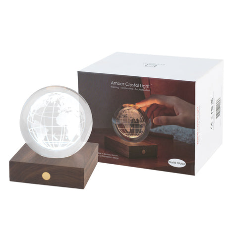 3D engraved globe design in a crystal ball on a wooden stand with its box.