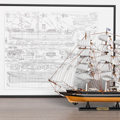 Detailed ship plan in a black frame, with a model ship in front.