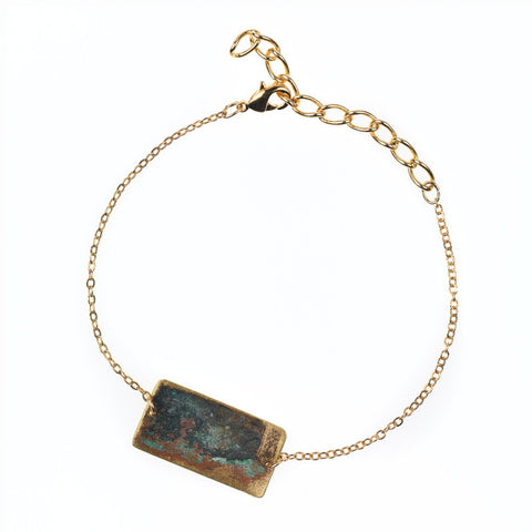 Gold chain bracelet with tarnished brass rectangle.