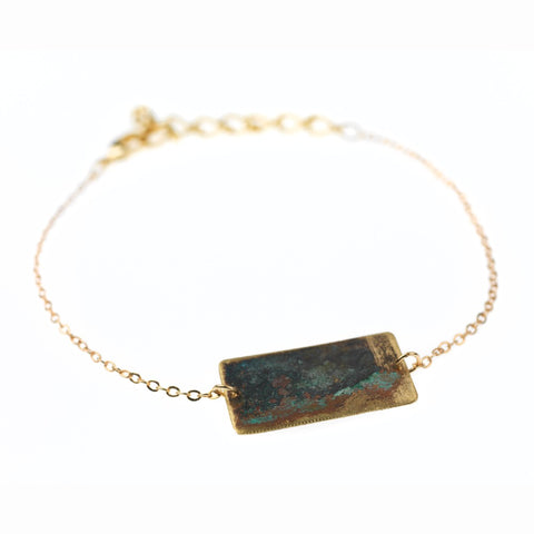 Gold chain bracelet with tarnished brass rectangle.