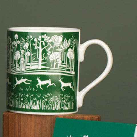 White mug with a green park illustration.