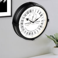 Greenwich Shepherd Gate 45cm Wall Clock, 24-Hour Analogue Dial on grey wall next to plant