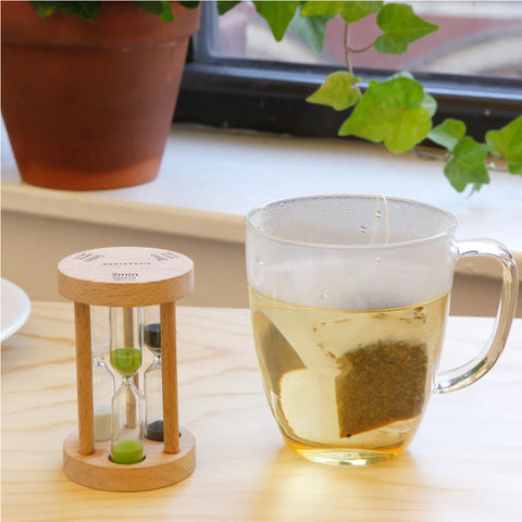 Trio sand timer next to a cup of tea.