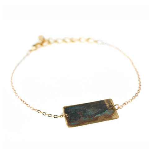 Gold chain bracelet with tarnished brass rectangle.