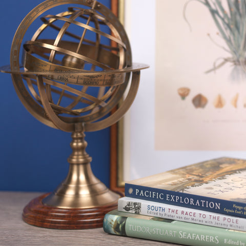 Large armillary sphere next to stack of books.