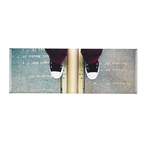 A photograph taken from above of two feet astride the Prime Meridian Line.