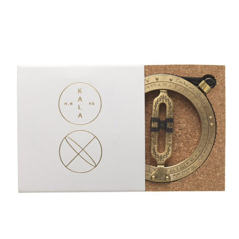 Brass folding pocket sundial in a white box.