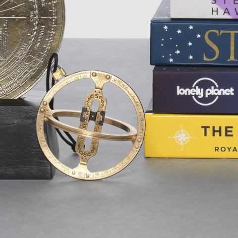 Brass folding pocket sundial with surrounded by books.